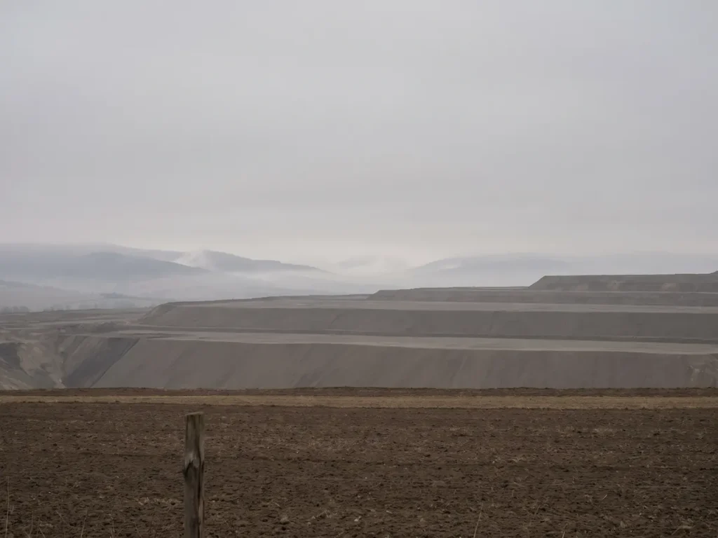 Marginea unei cariere de lignit din județul Gorj, unde terasele excavate se opresc la limita unui teren agricol privat