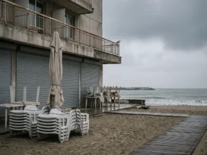 Hotel de pe litoral închis în extrasezon, cu terasa oblonită și șezlongurile stivuite