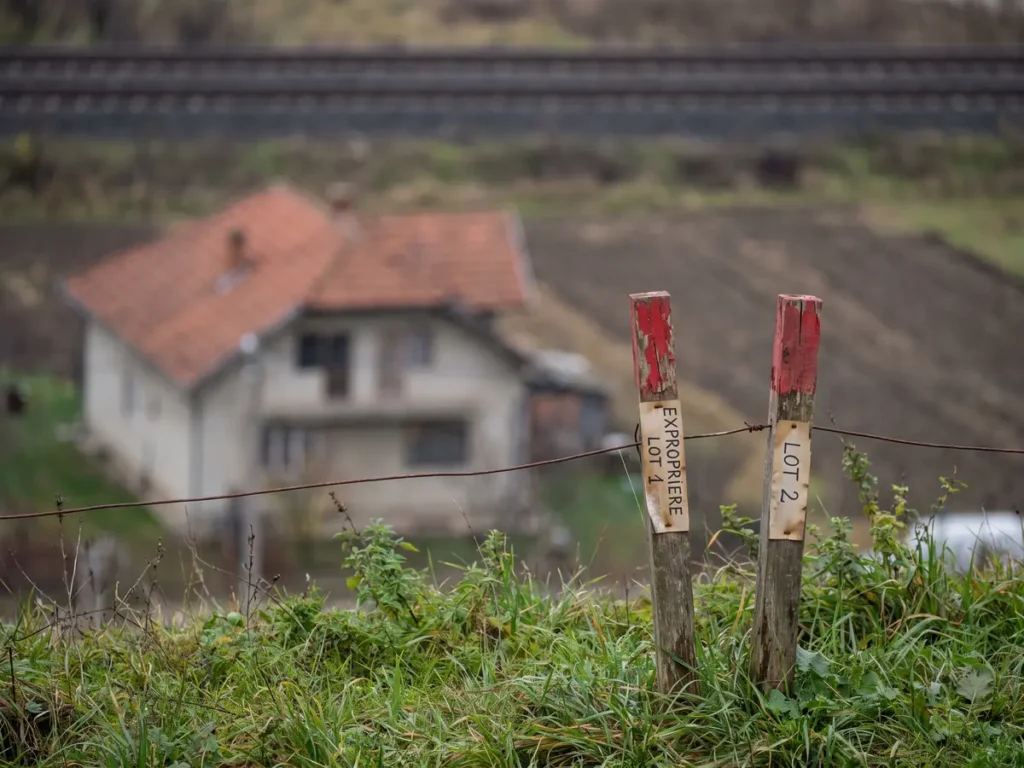 Țăruși de expropriere cu vârf roșu pe limita dintre două proprietăți vecine, lângă calea ferată de la marginea municipiului Cluj-Napoca